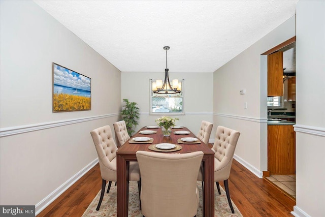 dining space featuring an inviting chandelier, wood-type flooring, and a textured ceiling