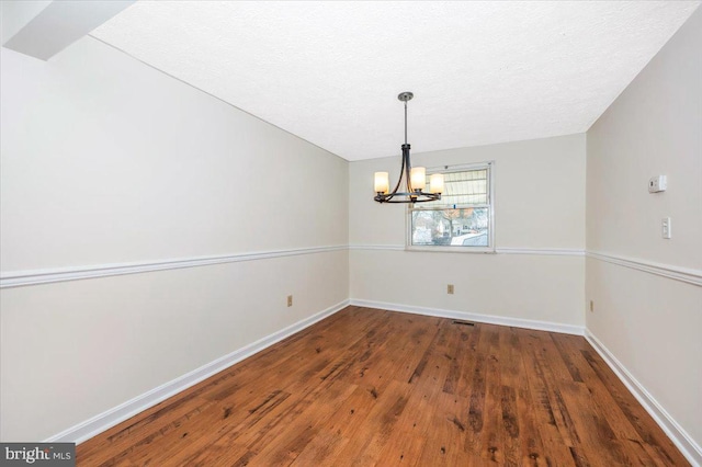 unfurnished dining area with dark hardwood / wood-style flooring, a chandelier, and a textured ceiling