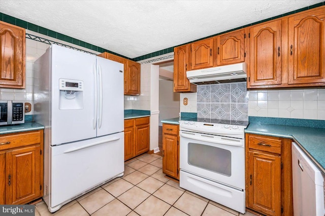 kitchen featuring light tile patterned flooring, decorative backsplash, white appliances, and a textured ceiling