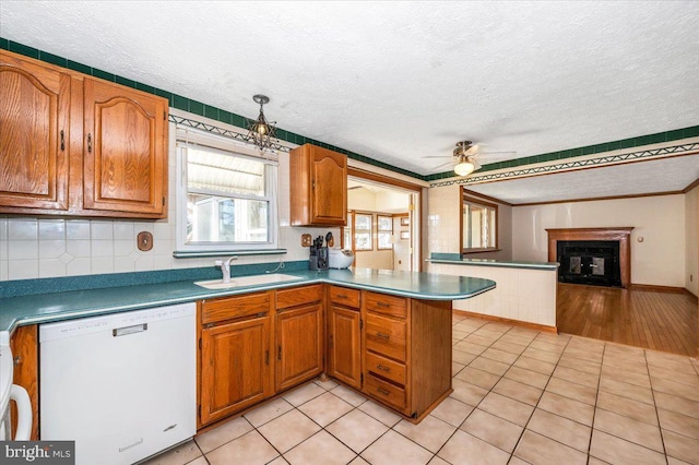 kitchen with light tile patterned floors, dishwasher, a textured ceiling, and sink