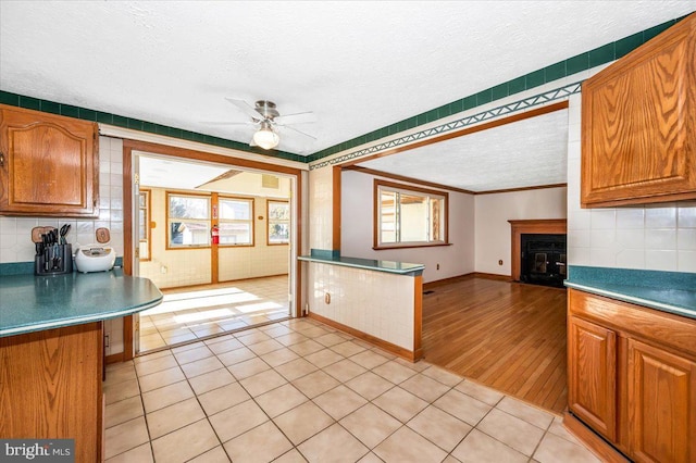 kitchen with light tile patterned floors, ceiling fan, backsplash, and a textured ceiling