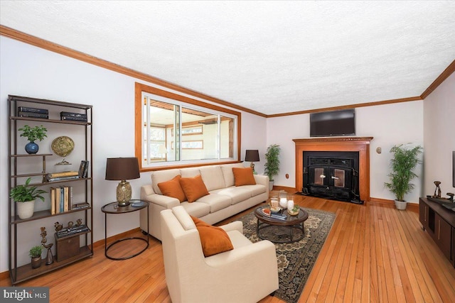 living room with light wood-type flooring, a textured ceiling, and ornamental molding