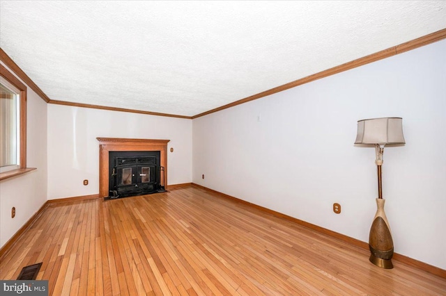 unfurnished living room with a textured ceiling, ornamental molding, and light hardwood / wood-style floors