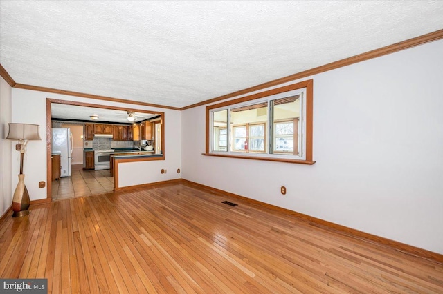 unfurnished living room featuring light hardwood / wood-style flooring, crown molding, and a textured ceiling