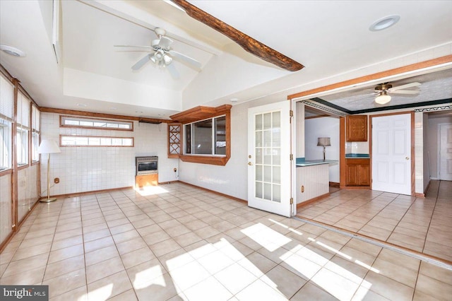 interior space with ceiling fan, light tile patterned floors, vaulted ceiling, and brick wall