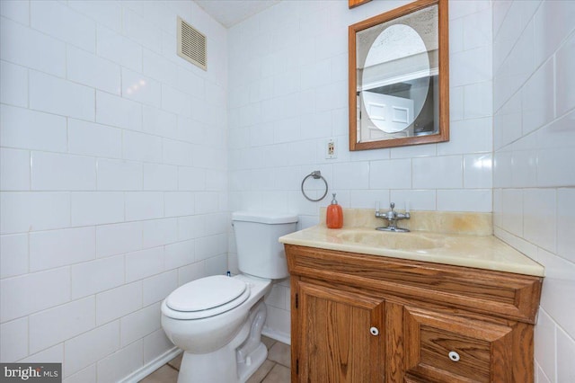 bathroom with toilet, tile walls, and vanity