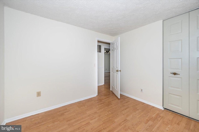 unfurnished bedroom with light hardwood / wood-style flooring and a textured ceiling