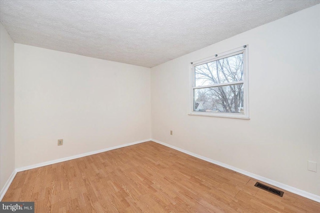 spare room with a textured ceiling and light hardwood / wood-style flooring