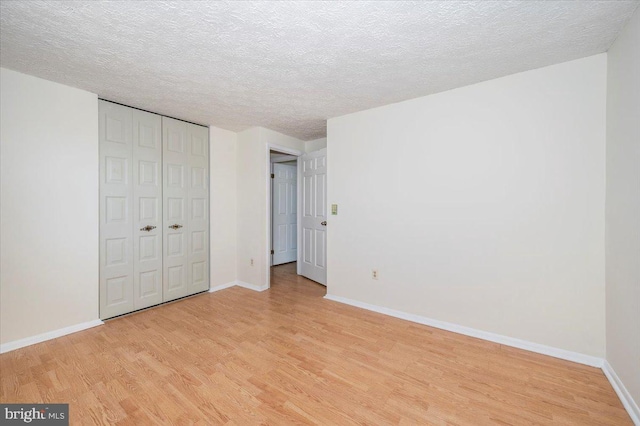 unfurnished bedroom featuring light hardwood / wood-style flooring, a closet, and a textured ceiling