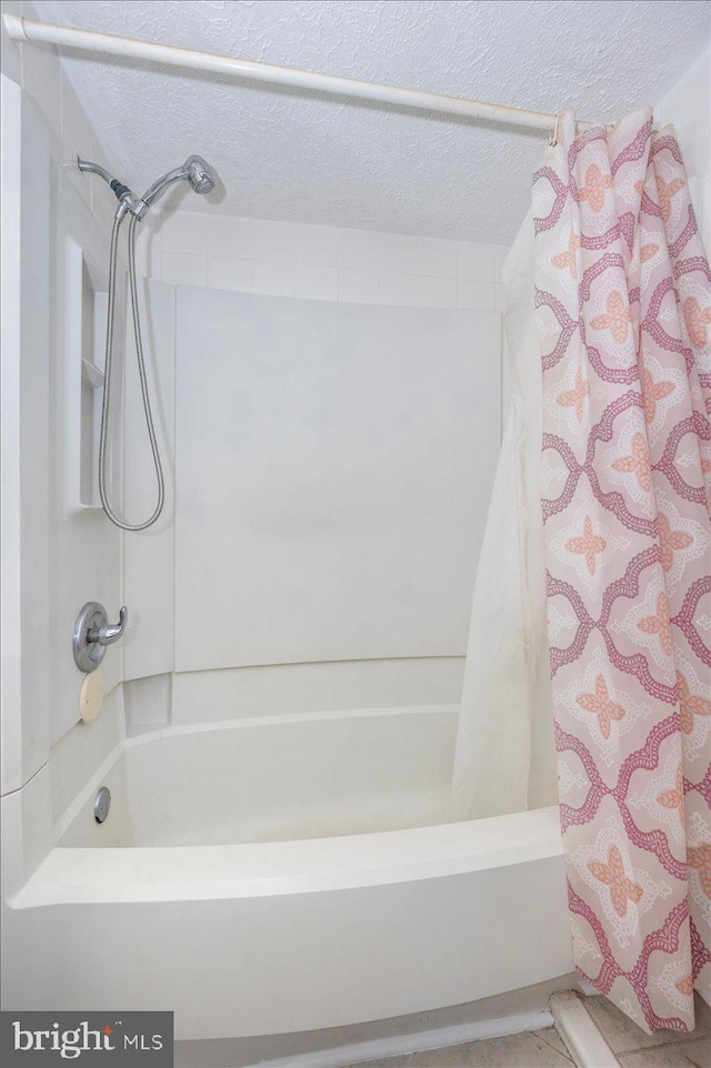 bathroom featuring a textured ceiling and shower / tub combo with curtain