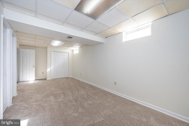 basement featuring a drop ceiling and light carpet