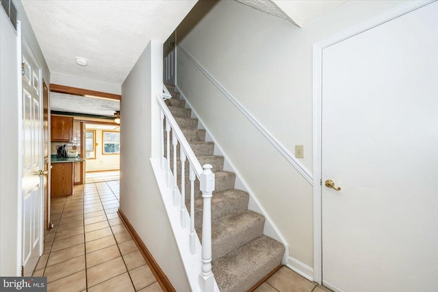 stairway featuring tile patterned flooring and a textured ceiling