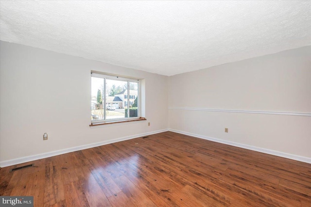 unfurnished room featuring wood-type flooring and a textured ceiling