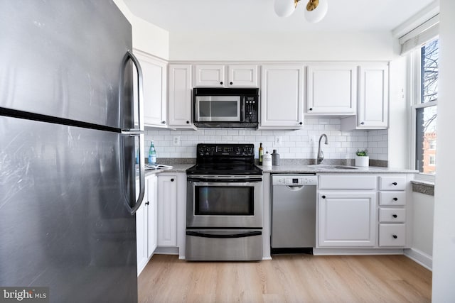 kitchen with white cabinetry, sink, stainless steel appliances, and light hardwood / wood-style floors