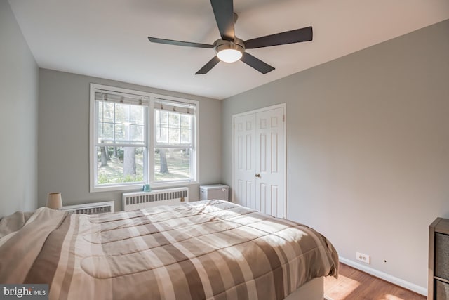 bedroom featuring radiator heating unit, a closet, ceiling fan, and light wood-type flooring