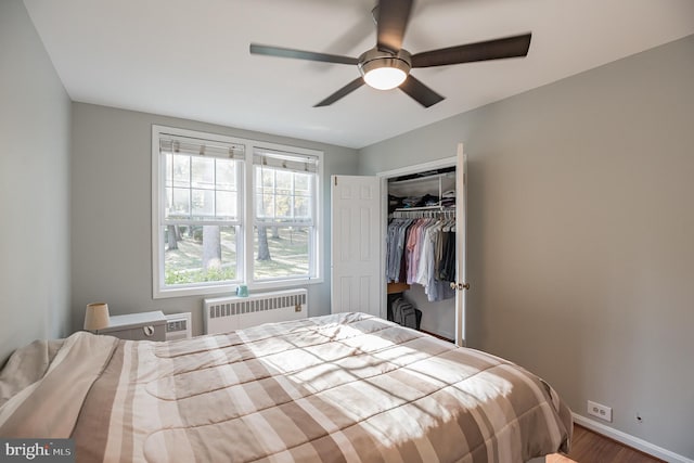 bedroom with ceiling fan, radiator heating unit, a closet, and wood-type flooring