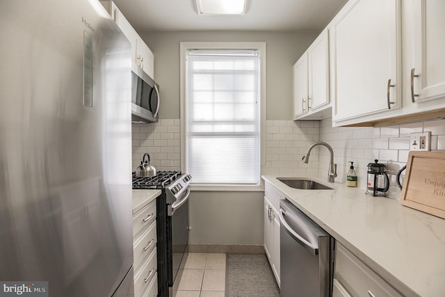 kitchen featuring light tile patterned flooring, appliances with stainless steel finishes, sink, white cabinets, and light stone counters