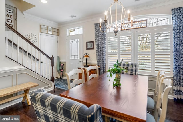 dining area with an inviting chandelier, ornamental molding, a wealth of natural light, and dark hardwood / wood-style flooring