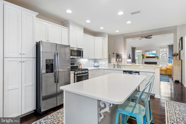 kitchen featuring appliances with stainless steel finishes, sink, a breakfast bar area, white cabinets, and kitchen peninsula