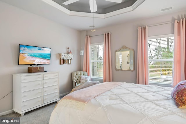 carpeted bedroom featuring multiple windows, a raised ceiling, and ceiling fan