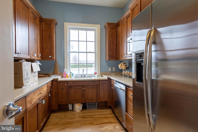 kitchen featuring appliances with stainless steel finishes, sink, and light hardwood / wood-style floors