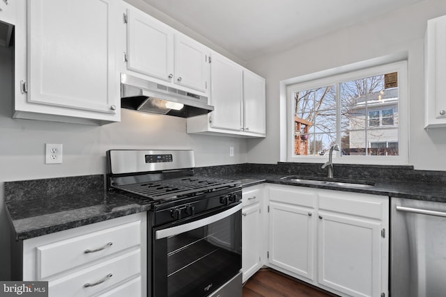 kitchen with dark stone countertops, appliances with stainless steel finishes, sink, and white cabinets