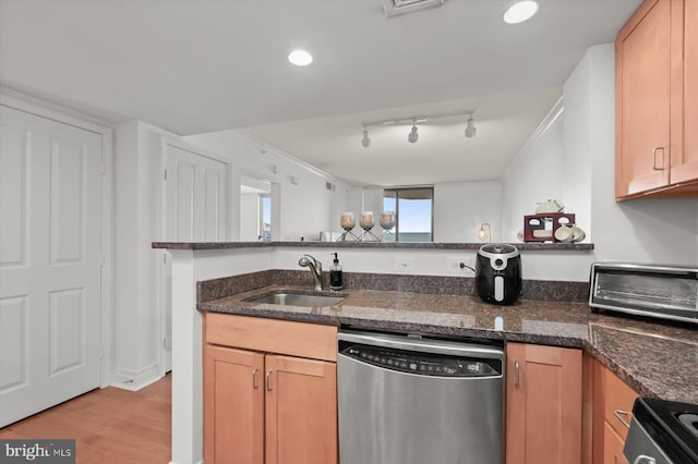 kitchen featuring sink, electric range oven, stainless steel dishwasher, dark stone counters, and light wood-type flooring