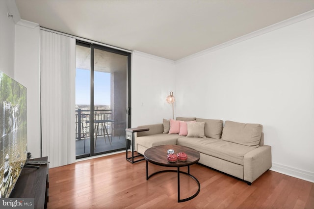 living room featuring hardwood / wood-style flooring, a wall of windows, and ornamental molding