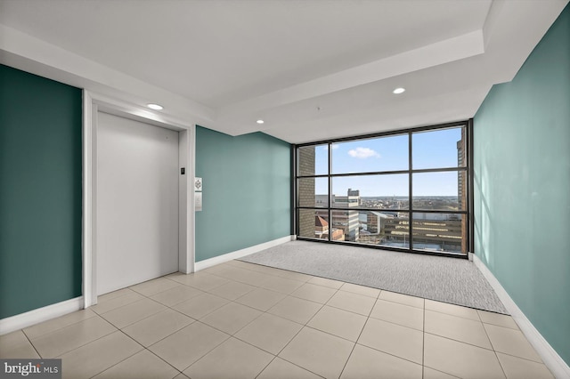 tiled spare room featuring elevator and a wall of windows