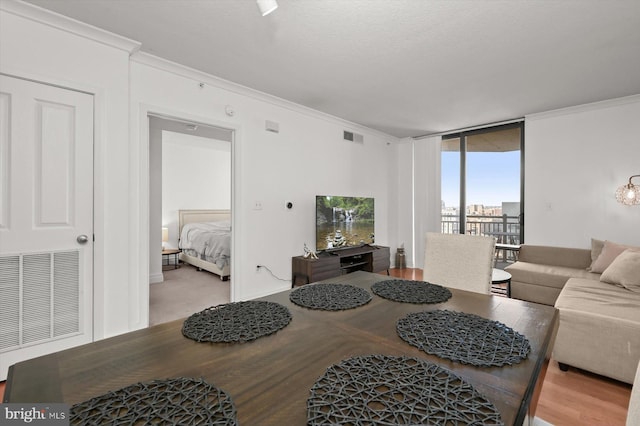 living room with ornamental molding, wood-type flooring, a textured ceiling, and a wall of windows