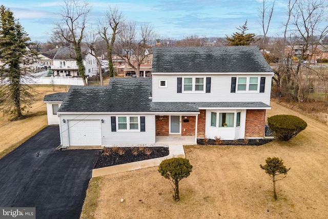 traditional-style house featuring a garage, brick siding, a shingled roof, driveway, and a residential view