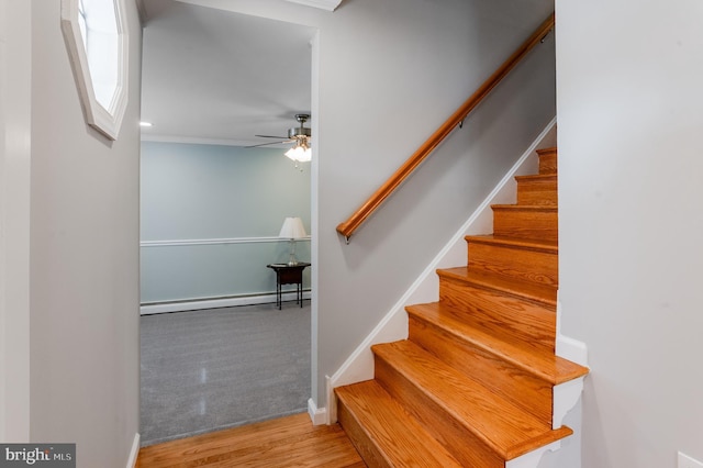 stairway with wood-type flooring, a baseboard heating unit, and ceiling fan