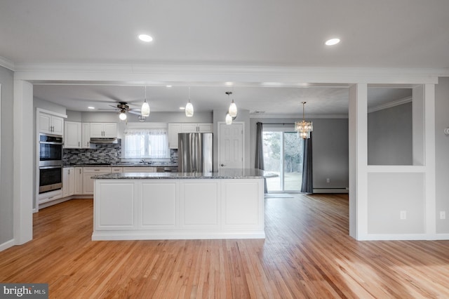 kitchen with a kitchen island, appliances with stainless steel finishes, pendant lighting, white cabinets, and dark stone counters