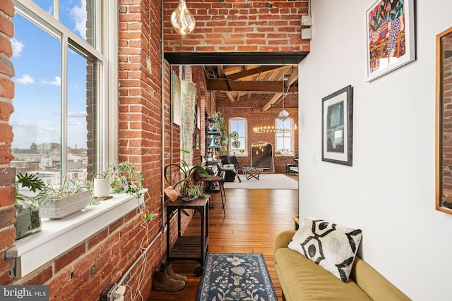 interior space with beamed ceiling, wood-type flooring, and brick wall