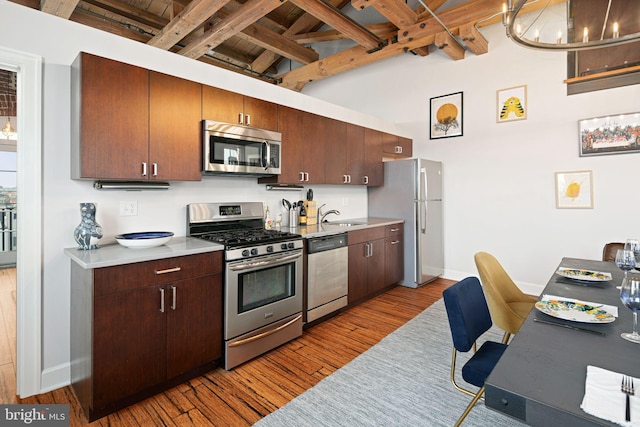 kitchen featuring appliances with stainless steel finishes, sink, hardwood / wood-style flooring, wood ceiling, and beam ceiling