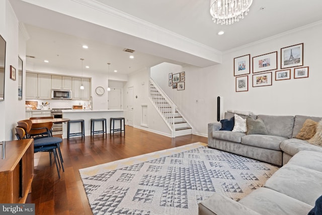 living room with crown molding, dark wood-type flooring, and a chandelier