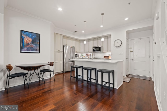 kitchen featuring appliances with stainless steel finishes, a breakfast bar, pendant lighting, a kitchen island with sink, and dark wood-type flooring