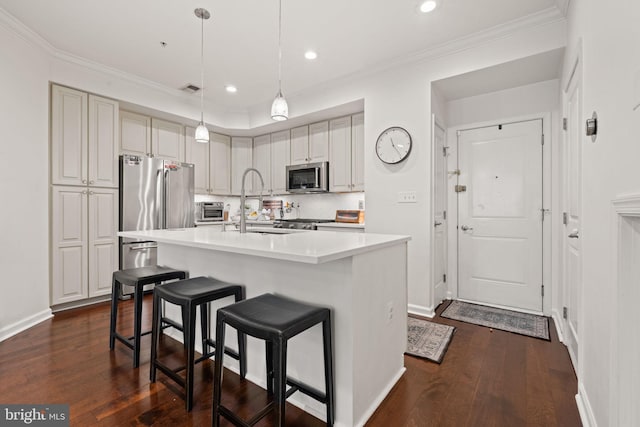 kitchen featuring sink, ornamental molding, appliances with stainless steel finishes, pendant lighting, and a kitchen island with sink