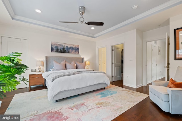 bedroom with ornamental molding, ceiling fan, dark hardwood / wood-style flooring, and a tray ceiling