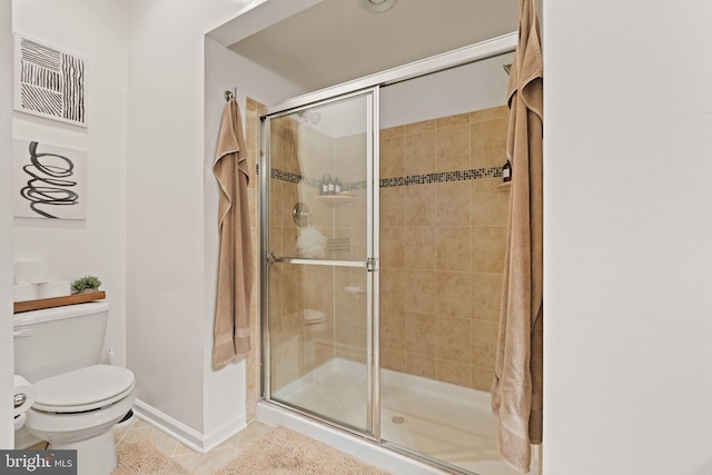 bathroom with tile patterned floors, toilet, and a shower with shower door