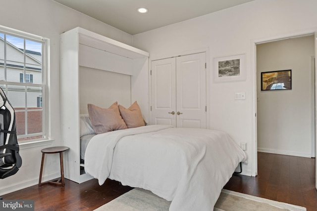 bedroom with dark hardwood / wood-style floors and a closet