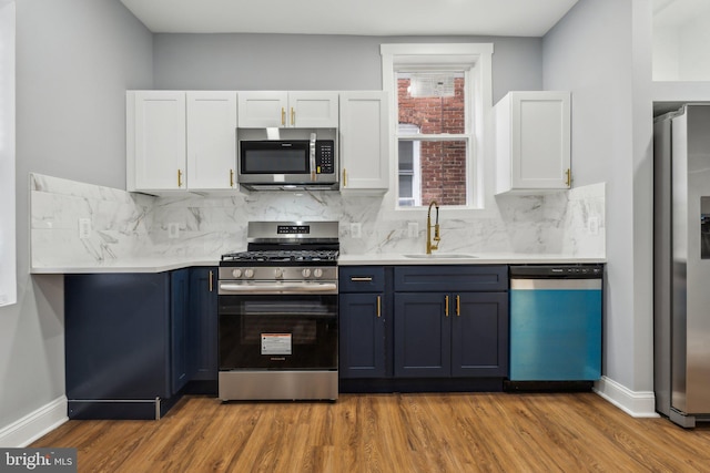 kitchen featuring white cabinetry, sink, stainless steel appliances, and blue cabinets