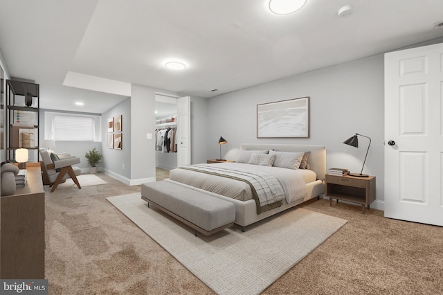 bedroom with a walk in closet, light colored carpet, and a closet