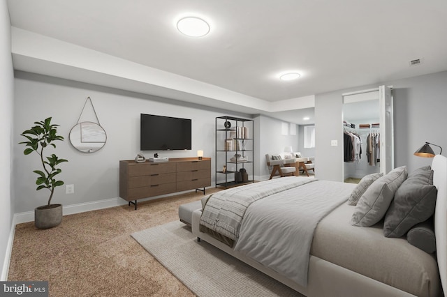 bedroom with light carpet and a spacious closet