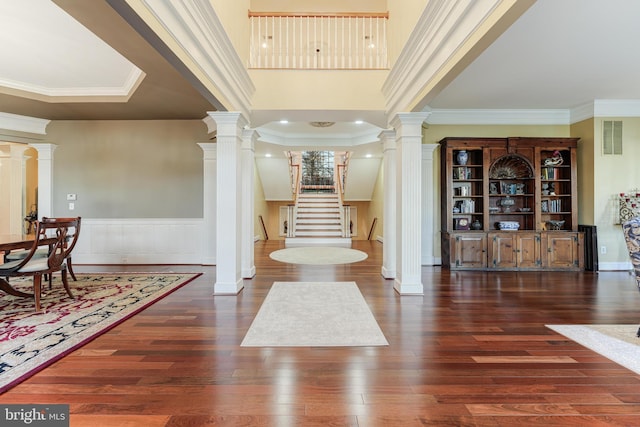 foyer with decorative columns, ornamental molding, and dark wood-type flooring