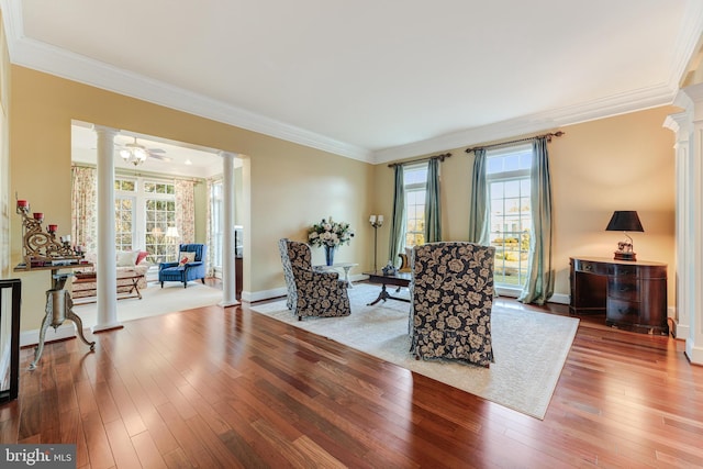 living area with ceiling fan, ornamental molding, wood-type flooring, and ornate columns