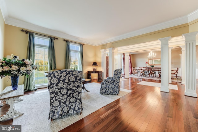 living room with decorative columns, crown molding, and hardwood / wood-style floors