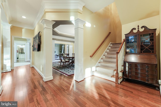 interior space featuring crown molding, hardwood / wood-style flooring, and decorative columns