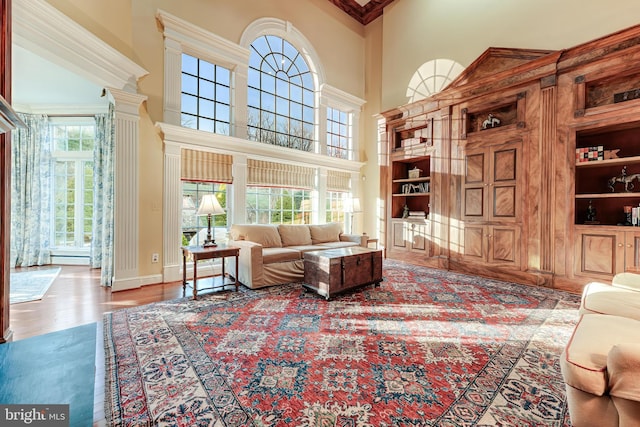 living room with built in features, light hardwood / wood-style flooring, and a high ceiling