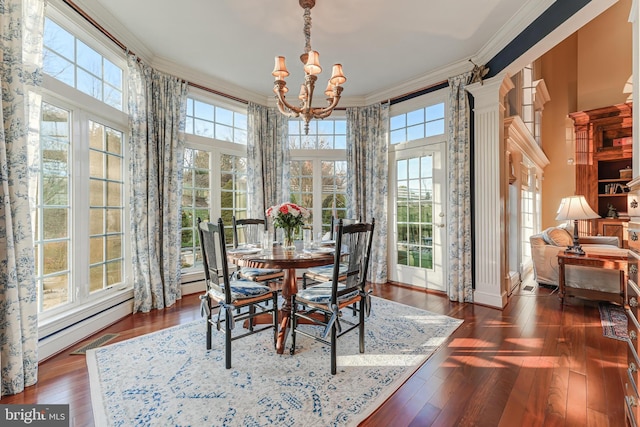 dining area with crown molding, dark wood-type flooring, a wealth of natural light, and a chandelier